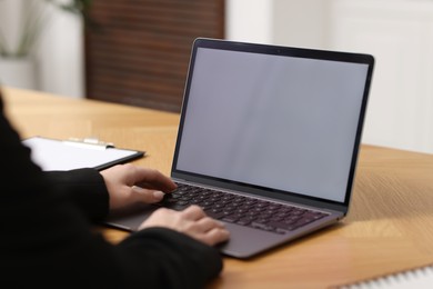 Photo of Businesswoman working with laptop at wooden table in office, closeup