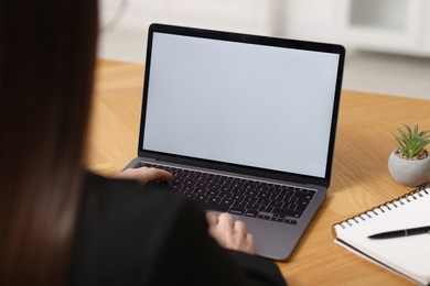 Photo of Businesswoman working with laptop at wooden table in office, closeup