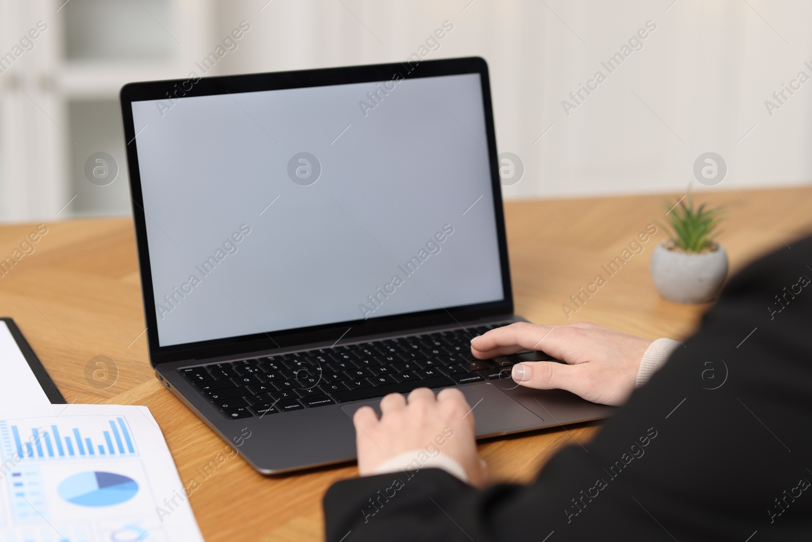 Photo of Businesswoman working with laptop at wooden table in office, closeup