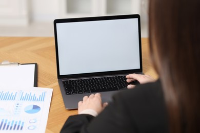 Photo of Businesswoman working with laptop at wooden table in office, closeup