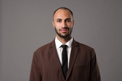 Portrait of businessman in brown jacket on gray background