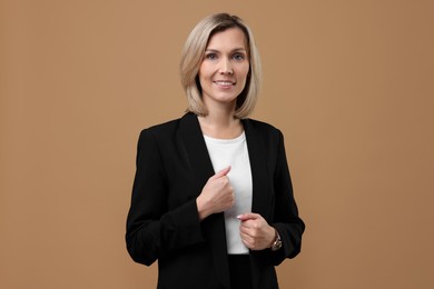 Portrait of businesswoman in jacket on beige background