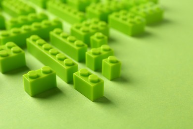 Photo of Constructor toy. Many building blocks on light green background, closeup