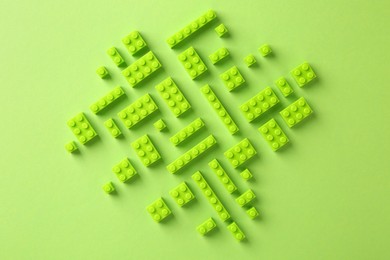 Photo of Constructor toy. Many building blocks on light green background, flat lay