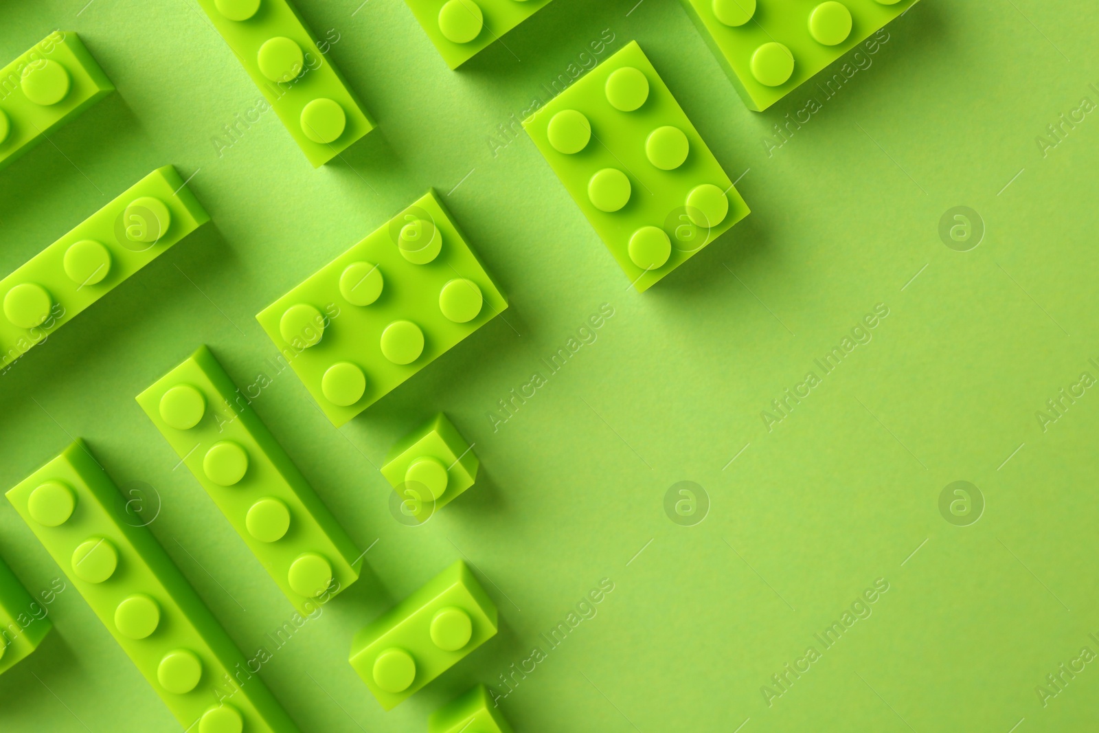 Photo of Constructor toy. Many building blocks on light green background, flat lay. Space for text