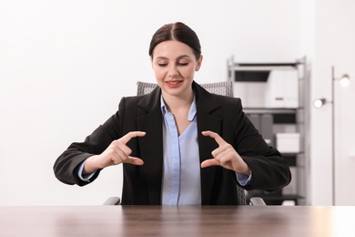 Beautiful woman showing something at wooden table in office