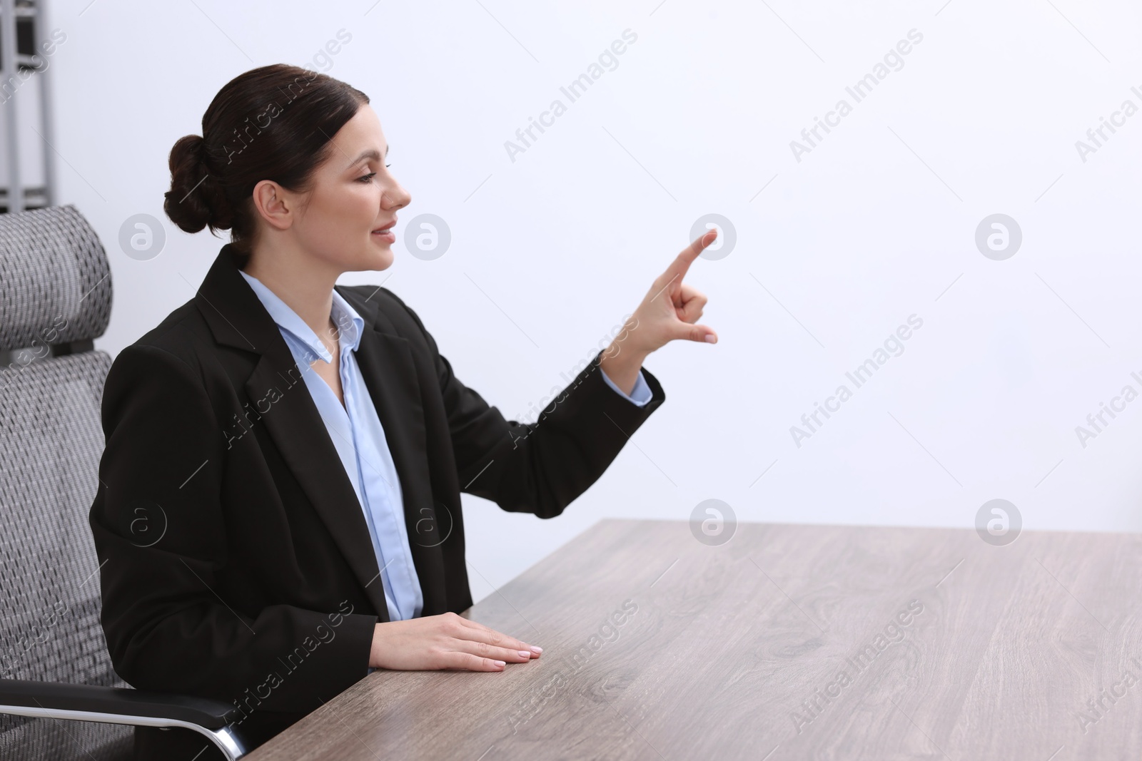 Photo of Beautiful woman pointing at something in office, space for text