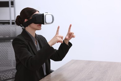 Woman using virtual reality headset in office, space for text