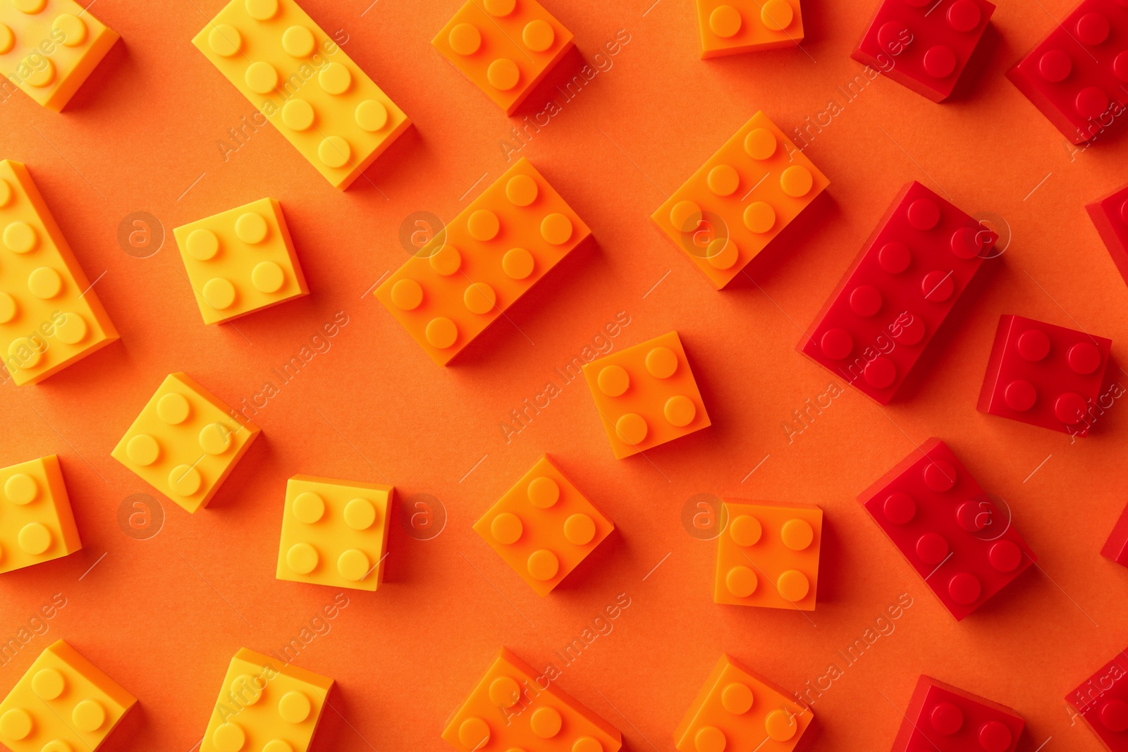 Photo of Construction toy. Colorful building bricks on orange background, flat lay