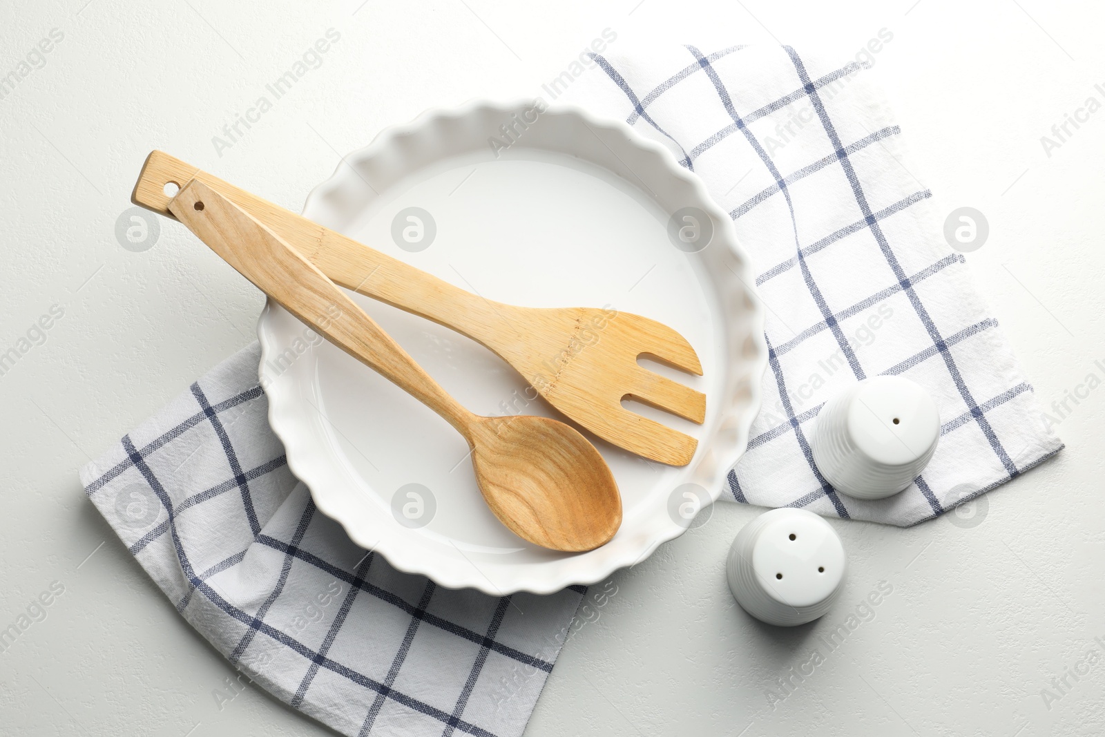 Photo of Ceramic casserole and other cooking utensils on white table, top view