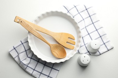 Photo of Ceramic casserole and other cooking utensils on white table, top view