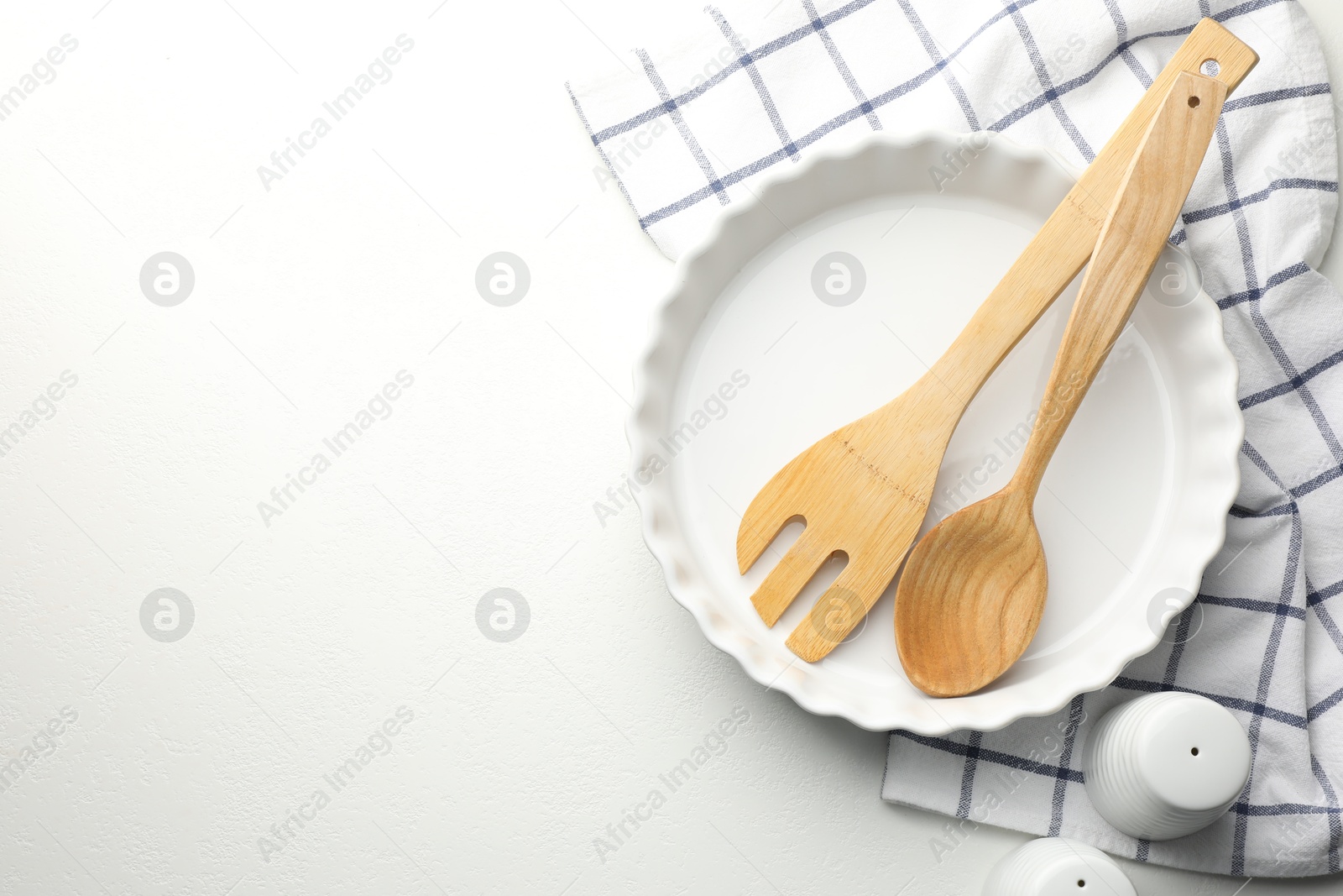 Photo of Ceramic casserole and other cooking utensils on white table, top view. Space for text