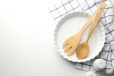 Photo of Ceramic casserole and other cooking utensils on white table, top view. Space for text