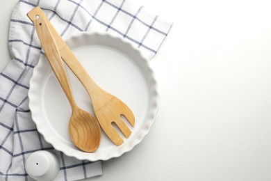 Photo of Ceramic casserole and other cooking utensils on white table, top view. Space for text