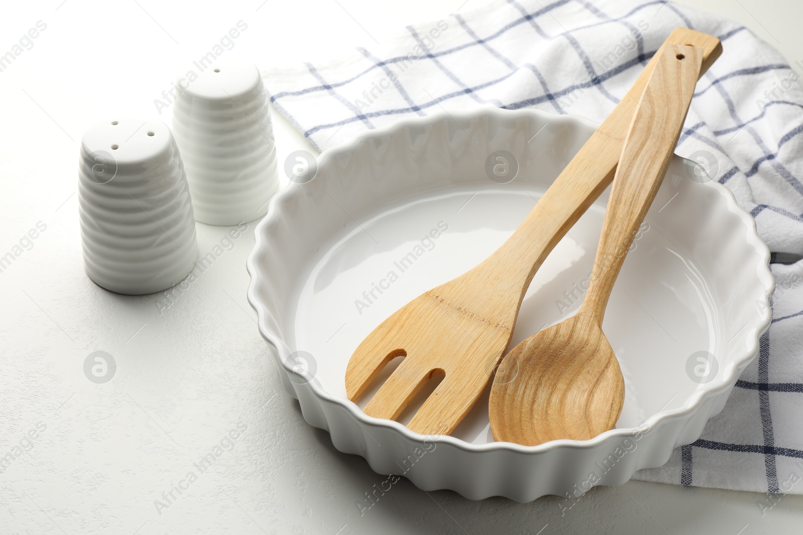 Photo of Ceramic casserole and other cooking utensils on white table, closeup