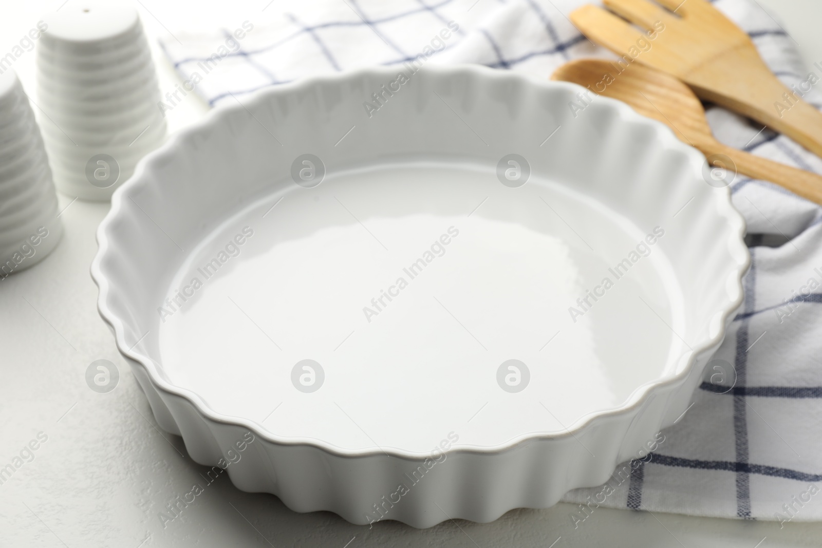 Photo of Ceramic casserole and other cooking utensils on white table, closeup