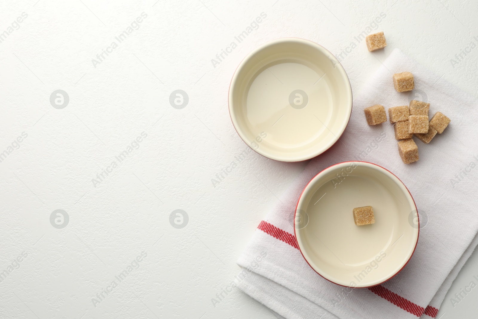 Photo of Ceramic casseroles and sugar cubes on white table, flat lay. Space for text