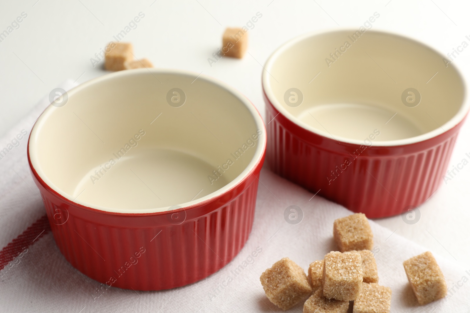 Photo of Ceramic casseroles and sugar cubes on white table, closeup