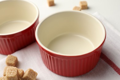 Photo of Ceramic casseroles and sugar cubes on table, closeup