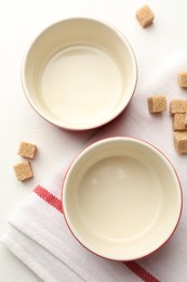 Photo of Ceramic casseroles and sugar cubes on white table, flat lay