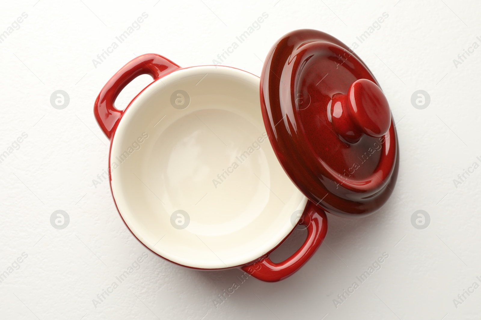 Photo of Ceramic casserole and lid on white table, top view