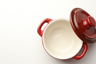 Photo of Ceramic casserole and lid on white table, top view. Space for text