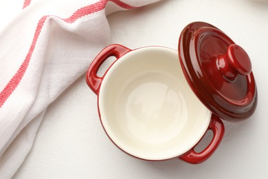 Photo of Ceramic casserole and lid on white table, top view