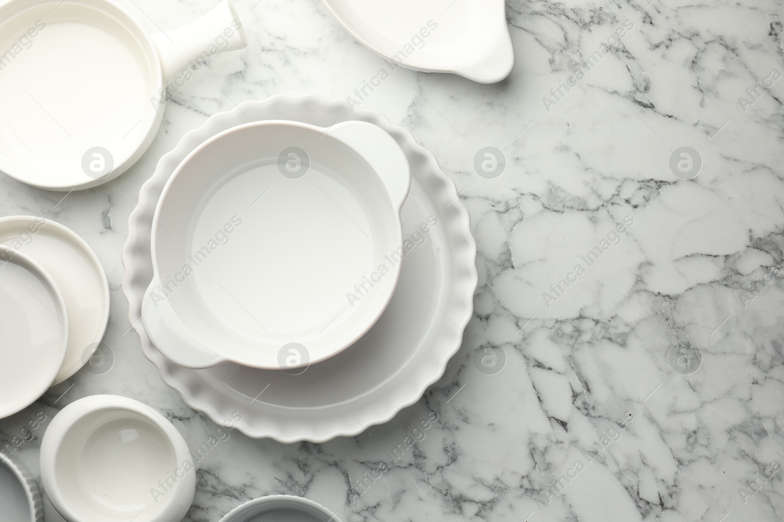 Photo of Different casseroles on white marble table, flat lay. Space for text