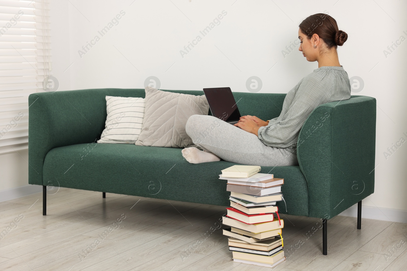 Photo of Student in headphones studying with laptop on sofa at home