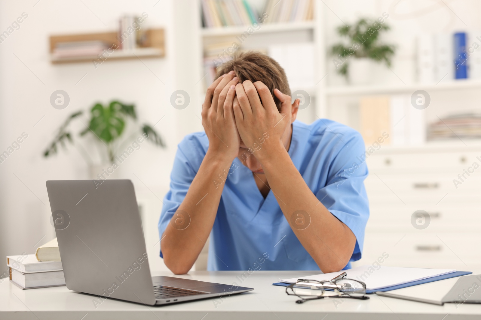 Photo of Medical student in uniform studying at table indoors