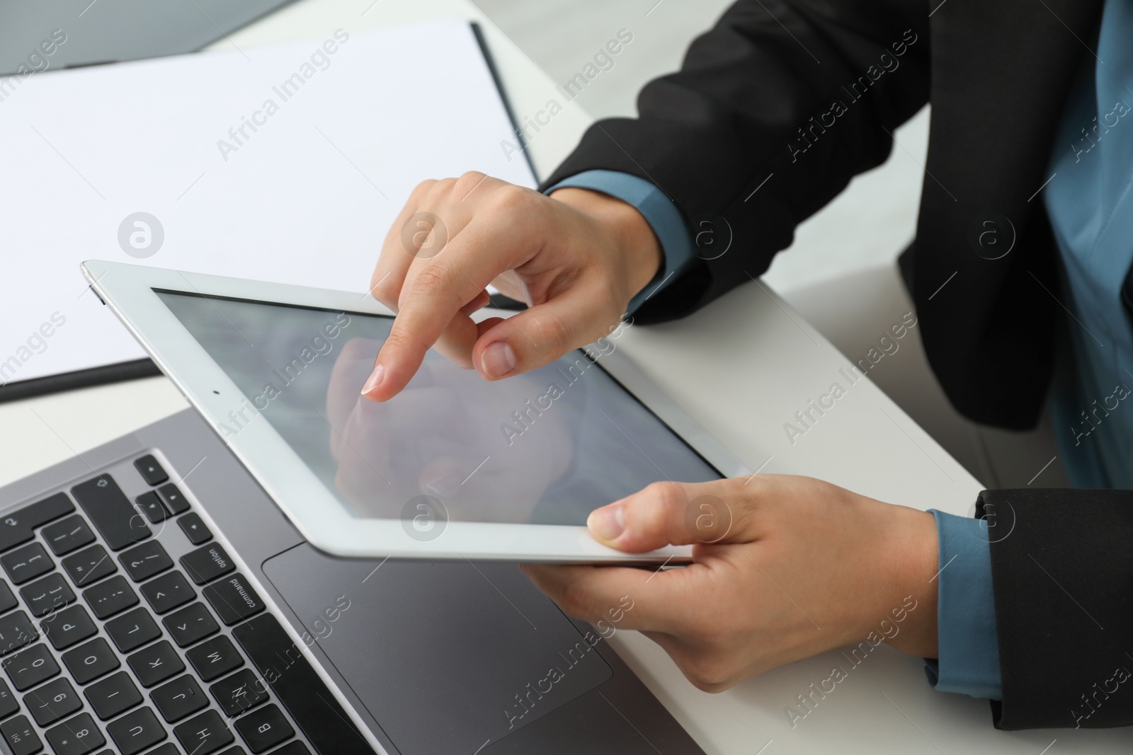 Photo of Businesswoman using tablet at white table indoors, closeup. Modern technology