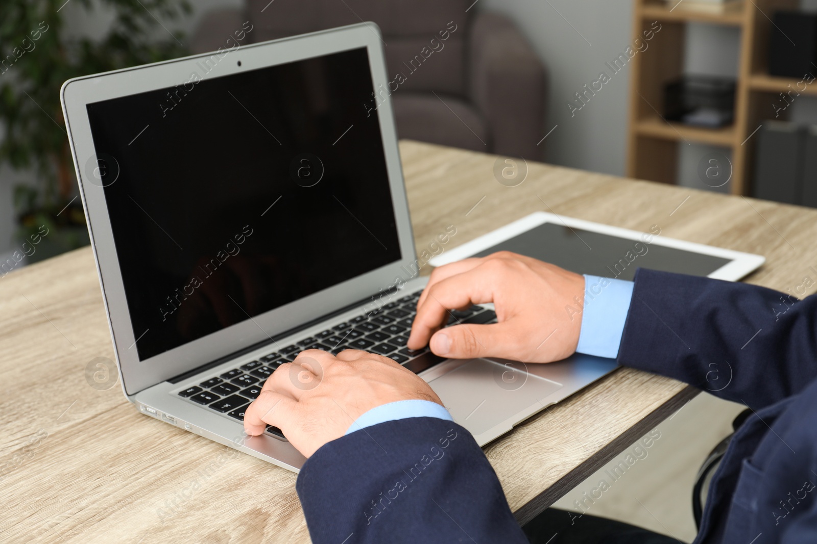 Photo of Businessman using laptop at wooden table, closeup. Modern technology