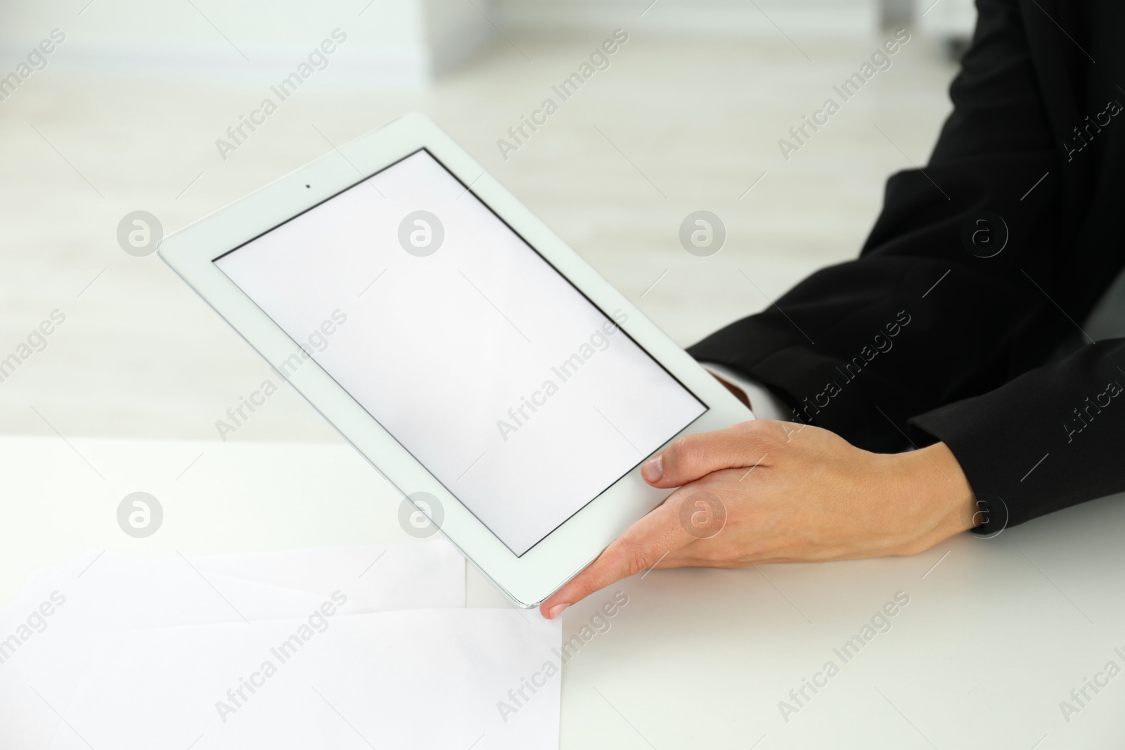 Photo of Businesswoman using tablet at white table indoors, closeup. Modern technology