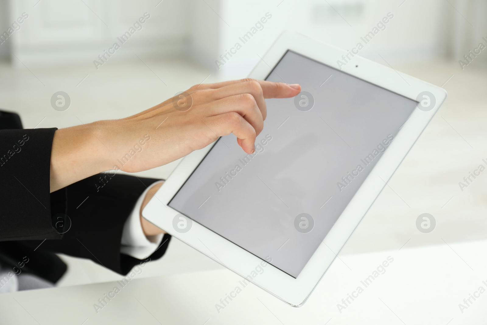 Photo of Businesswoman using tablet at white table indoors, closeup. Modern technology