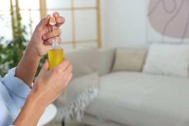 Photo of Young man taking CBD tincture indoors, closeup. Space for text