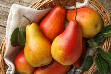 Photo of Ripe juicy pears in wicker basket on table, top view