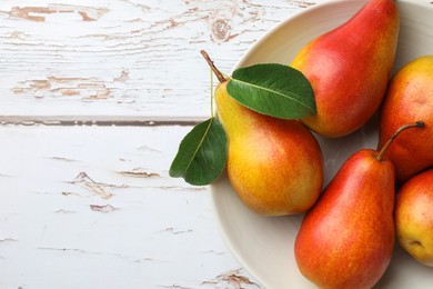 Photo of Ripe juicy pears in bowl on light wooden table, top view. Space for text