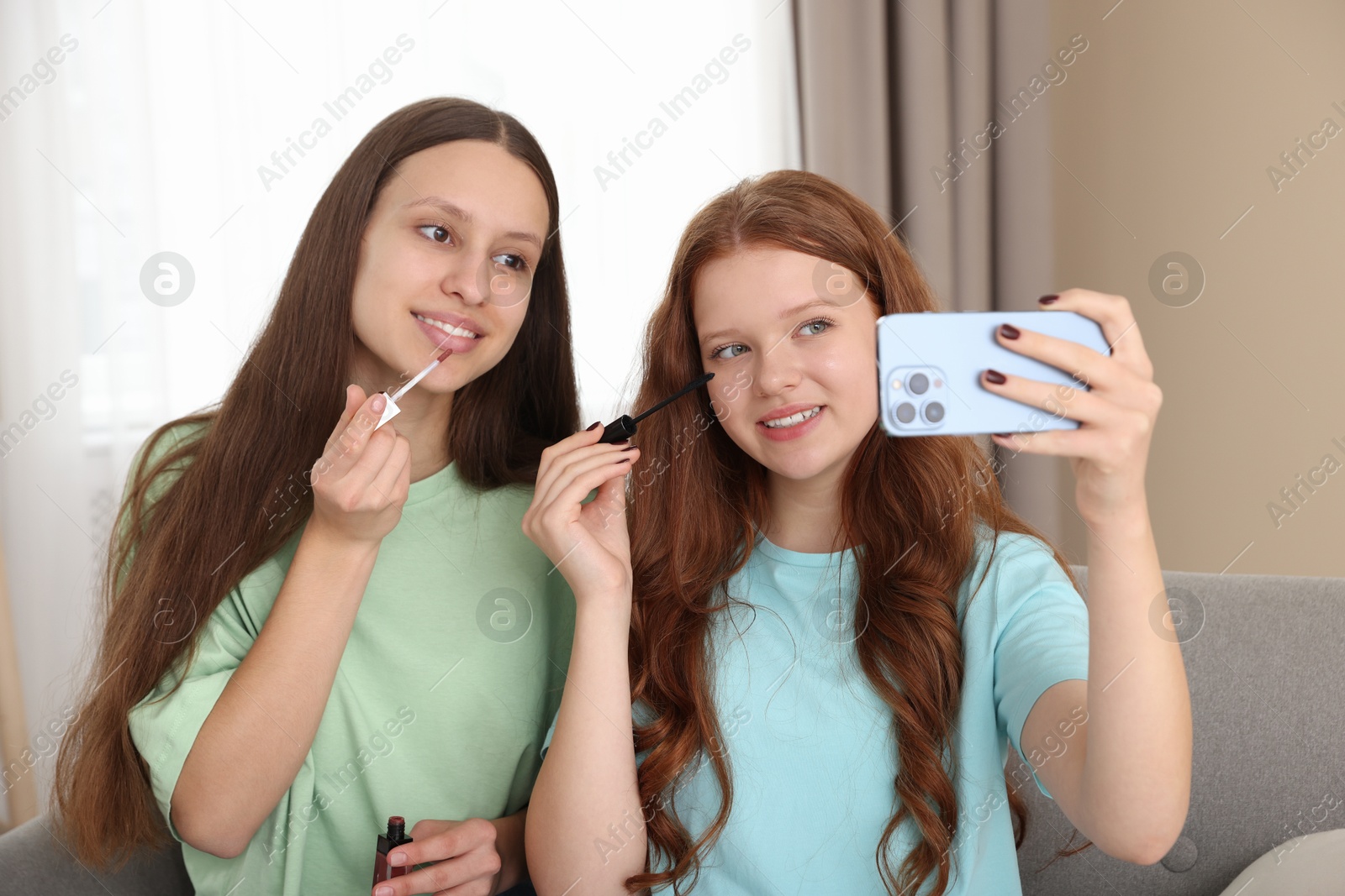 Photo of Teenage girls applying makeup products and taking selfie indoors