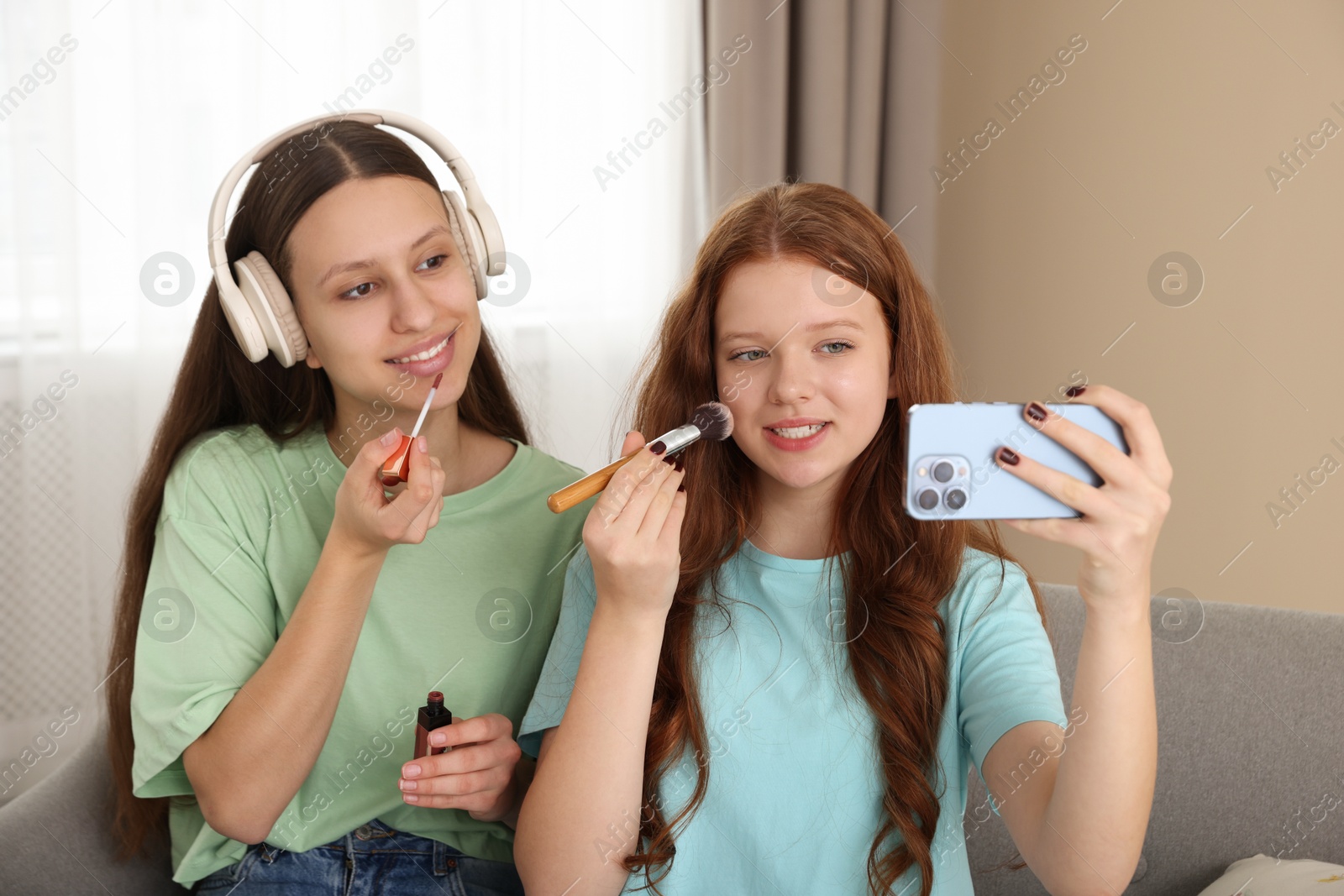 Photo of Teenage girls applying makeup products and taking selfie indoors