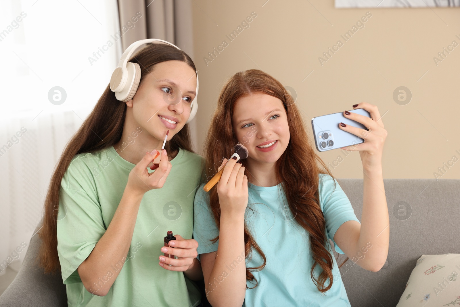 Photo of Teenage girls applying makeup products and taking selfie indoors