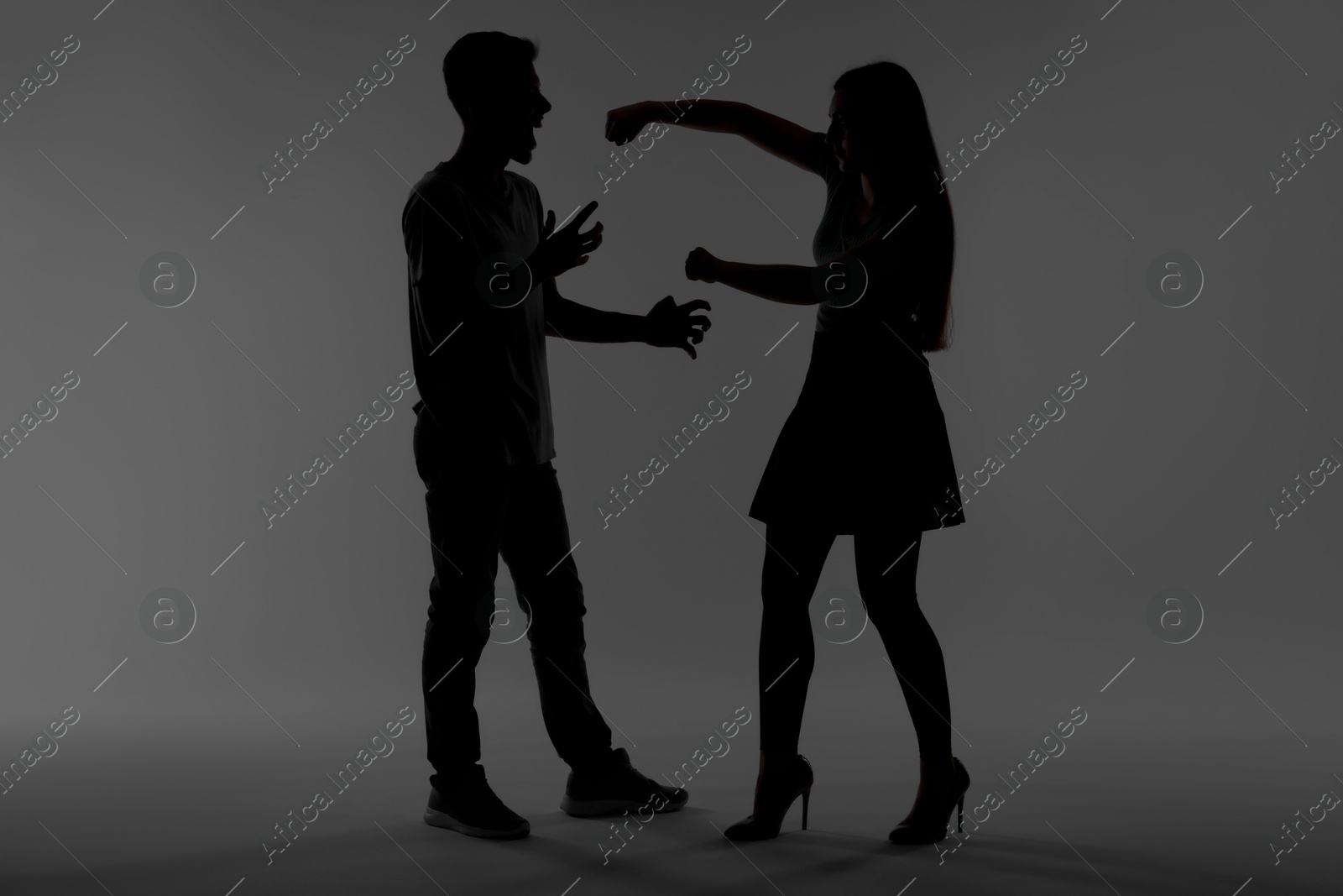 Photo of Domestic violence. Silhouette of couple quarreling on grey background