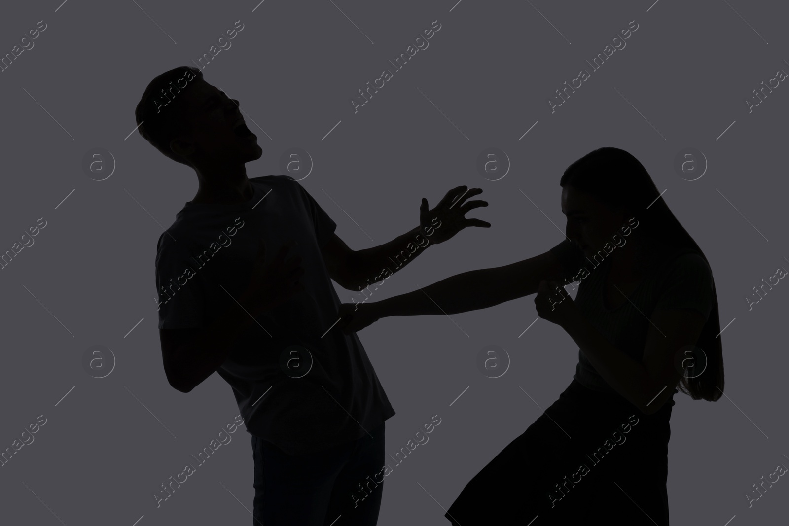 Photo of Domestic violence. Silhouette of couple quarreling on grey background