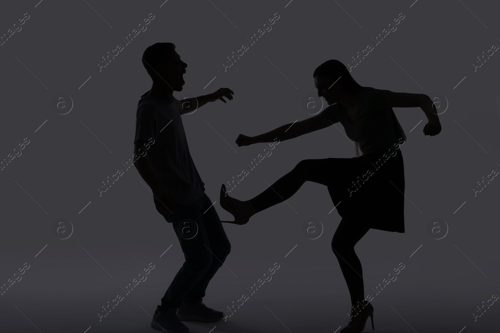 Photo of Domestic violence. Silhouette of couple quarreling on grey background