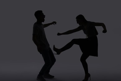 Photo of Domestic violence. Silhouette of couple quarreling on grey background