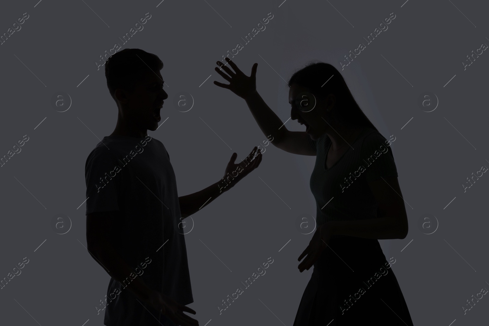 Photo of Domestic violence. Silhouette of couple quarreling on grey background