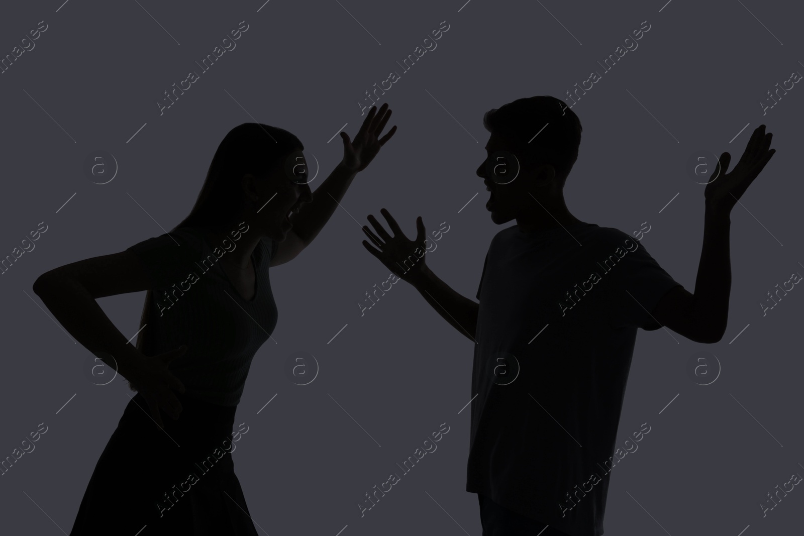 Photo of Domestic violence. Silhouette of couple quarreling on grey background