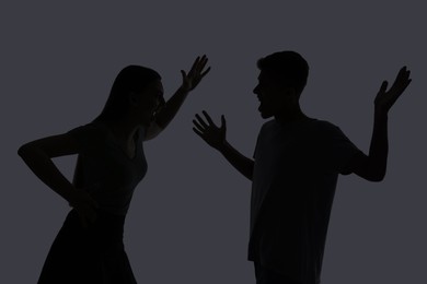 Photo of Domestic violence. Silhouette of couple quarreling on grey background