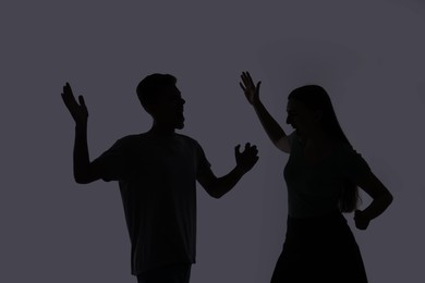 Photo of Domestic violence. Silhouette of couple quarreling on grey background