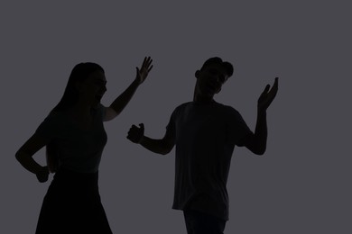 Photo of Domestic violence. Silhouette of couple quarreling on grey background