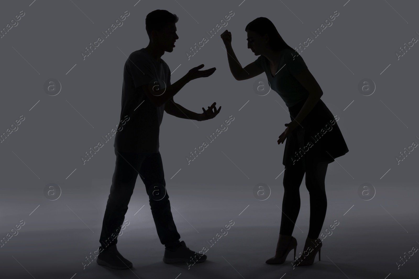 Photo of Domestic violence. Silhouette of couple quarreling on grey background